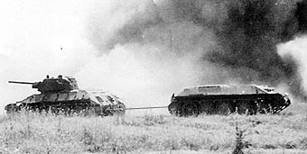БРЭМ, переделанная из обычного Т-34, тащит на буксире поврежденный танк, обращенный ко врагу лобовой броней. Курск. Июль 1943.