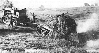 Пара тракторов СТЗ-65 вытаскивают застрявший Т-34. Хотя второго трактора и не видно, но виден его трос. Это танк одной из танковых частей 50-й армии, летом 1942-го года ведшей бои с немецкой группой армий Центр. Сухиничи, район Калуги. 